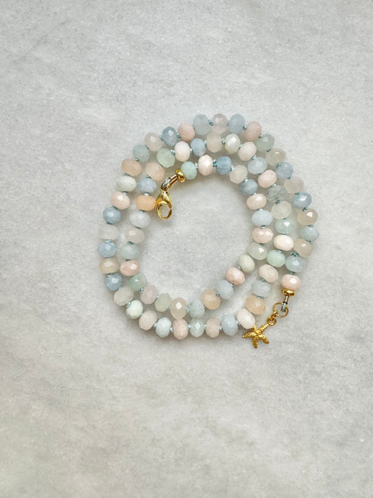 A hand-knotted necklace made of morganite and aquamarine gemstones on light blue silk thread with a gold vermeil clasp and starfish charm.
