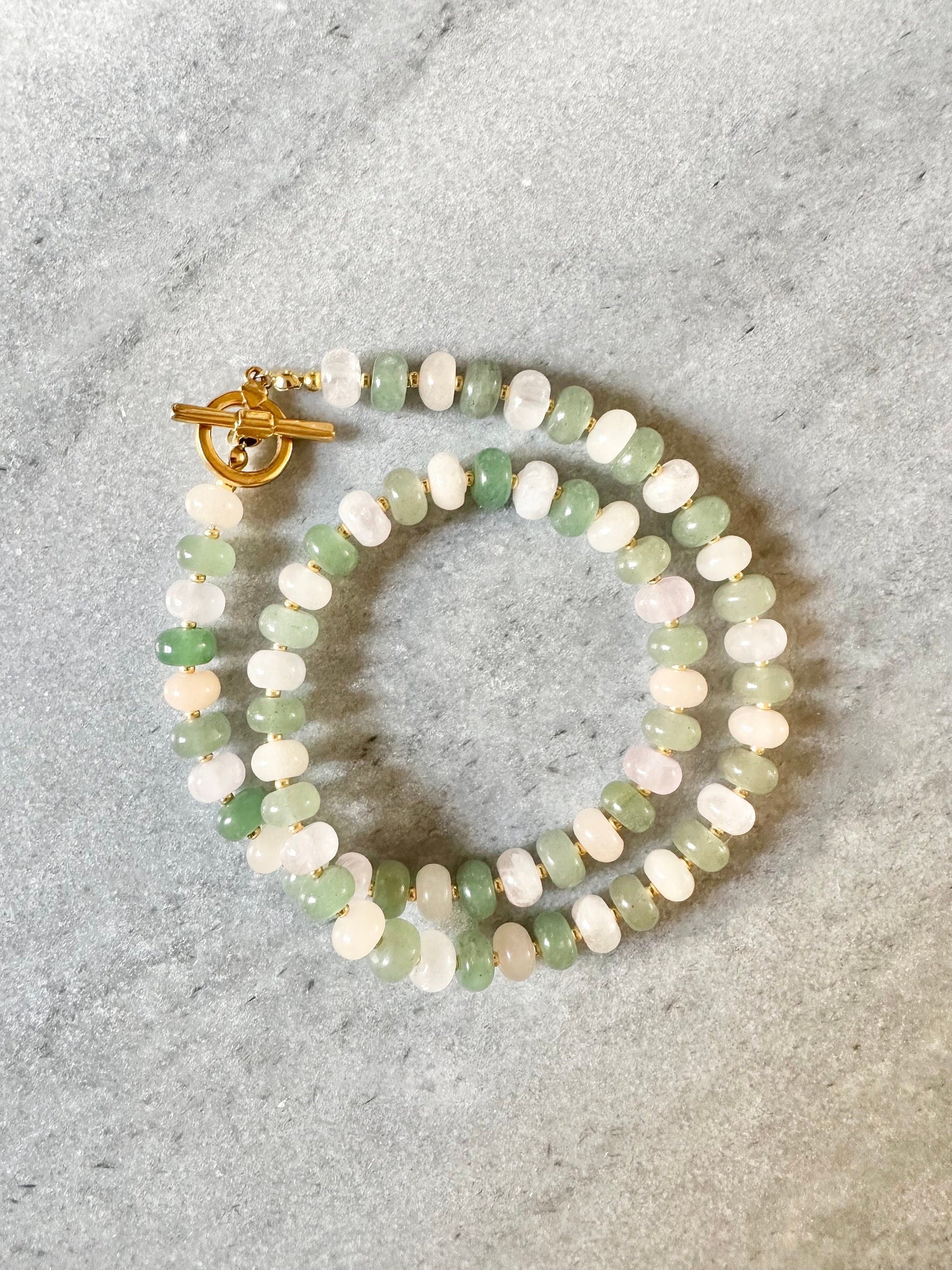 A beaded necklace with a green and pink aventurine and rose quartz design, featuring a gold plated toggle clasp.