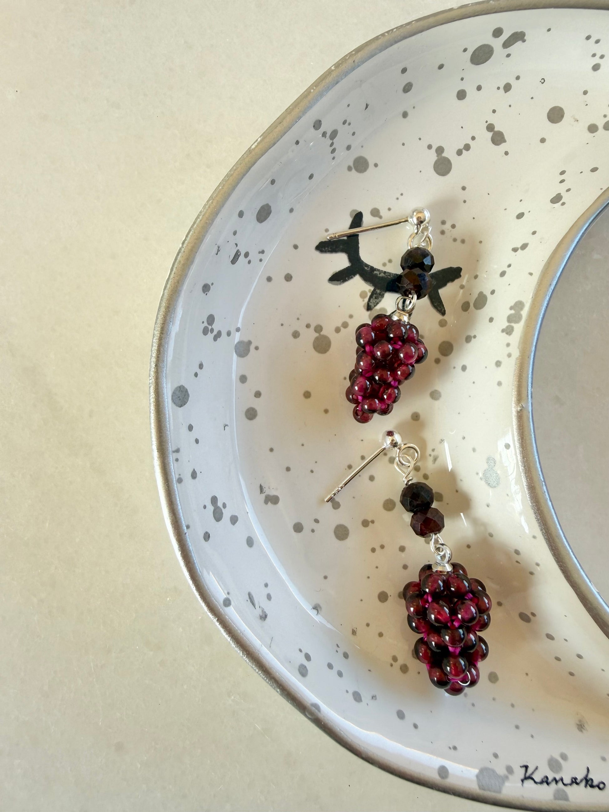 Pair of earrings with grape design on a speckled plate