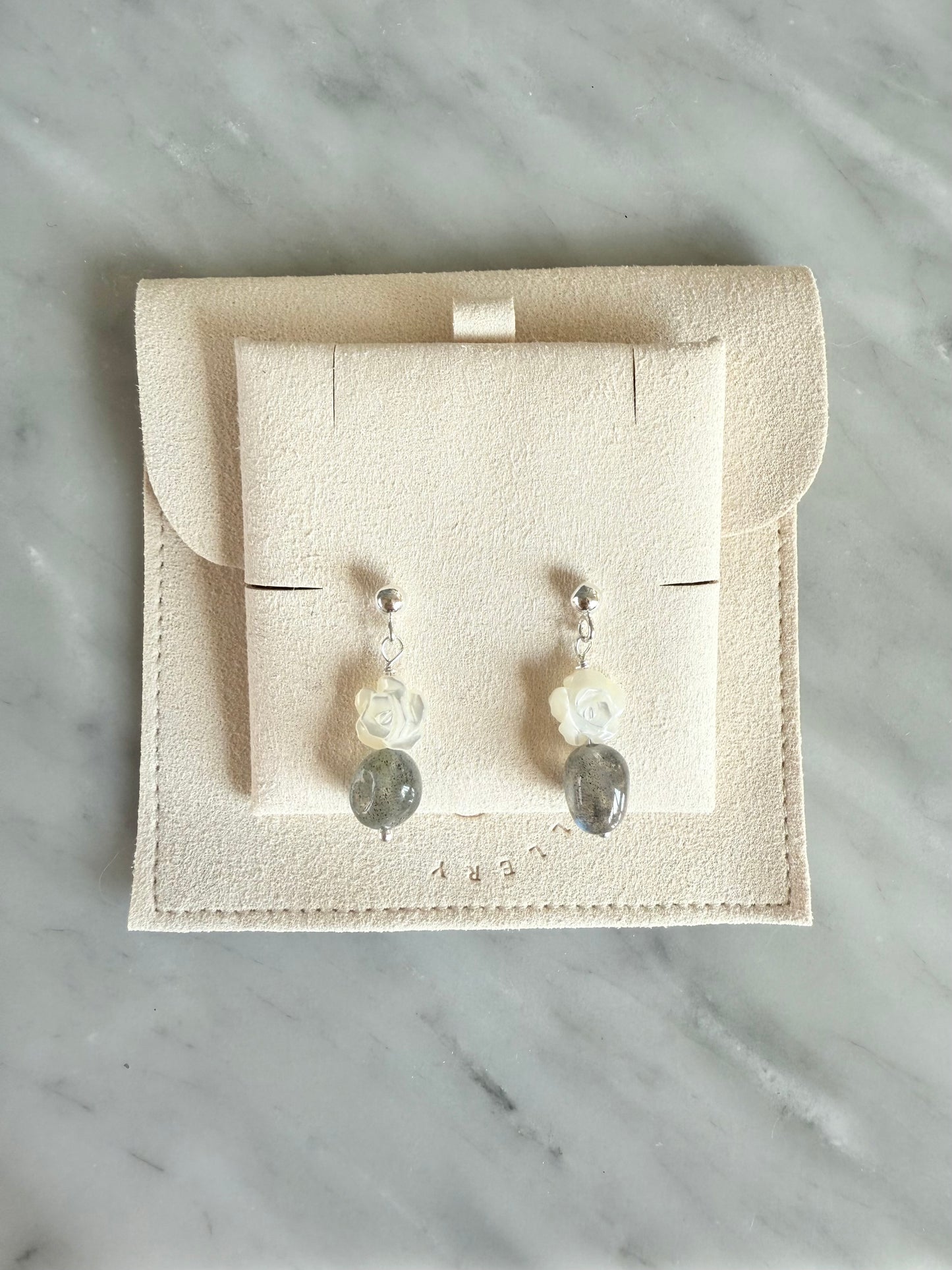 Pair of earrings on a display card with a marble background