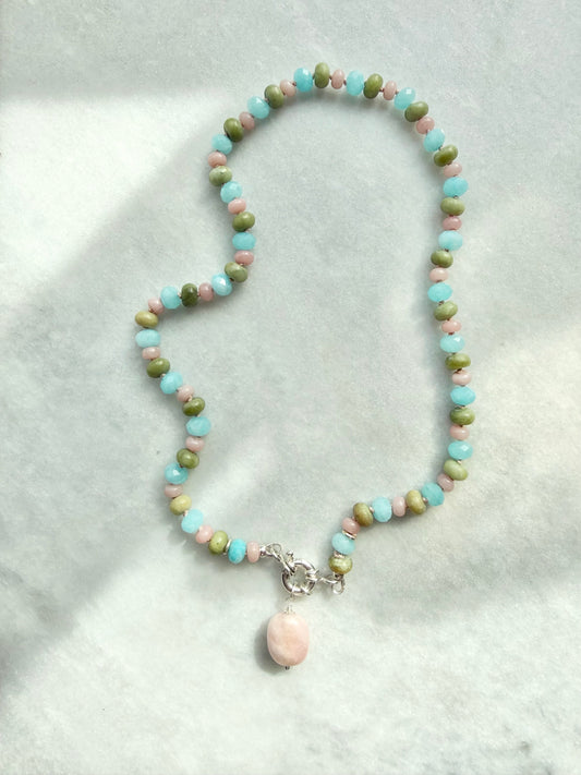 Beaded necklace with a pink pendant on a light gray background