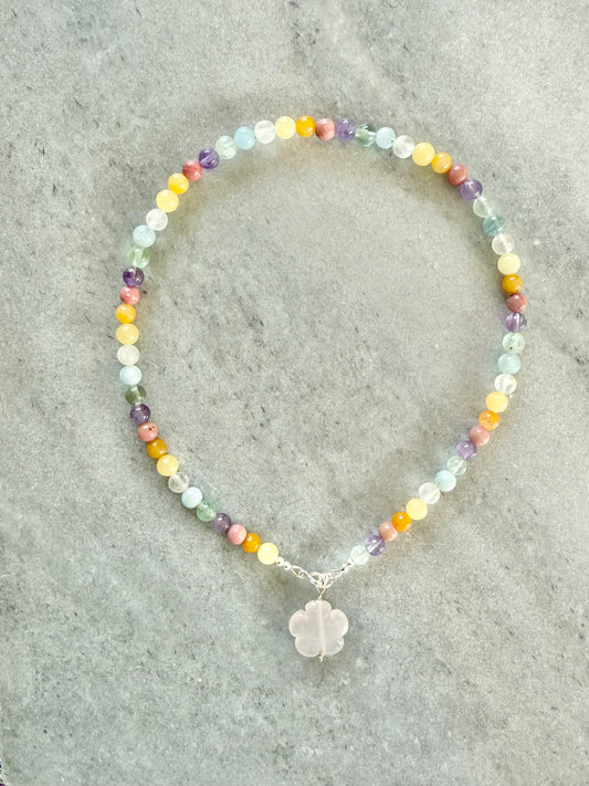 Multicolored beaded necklace with a silver charm on a gray surface