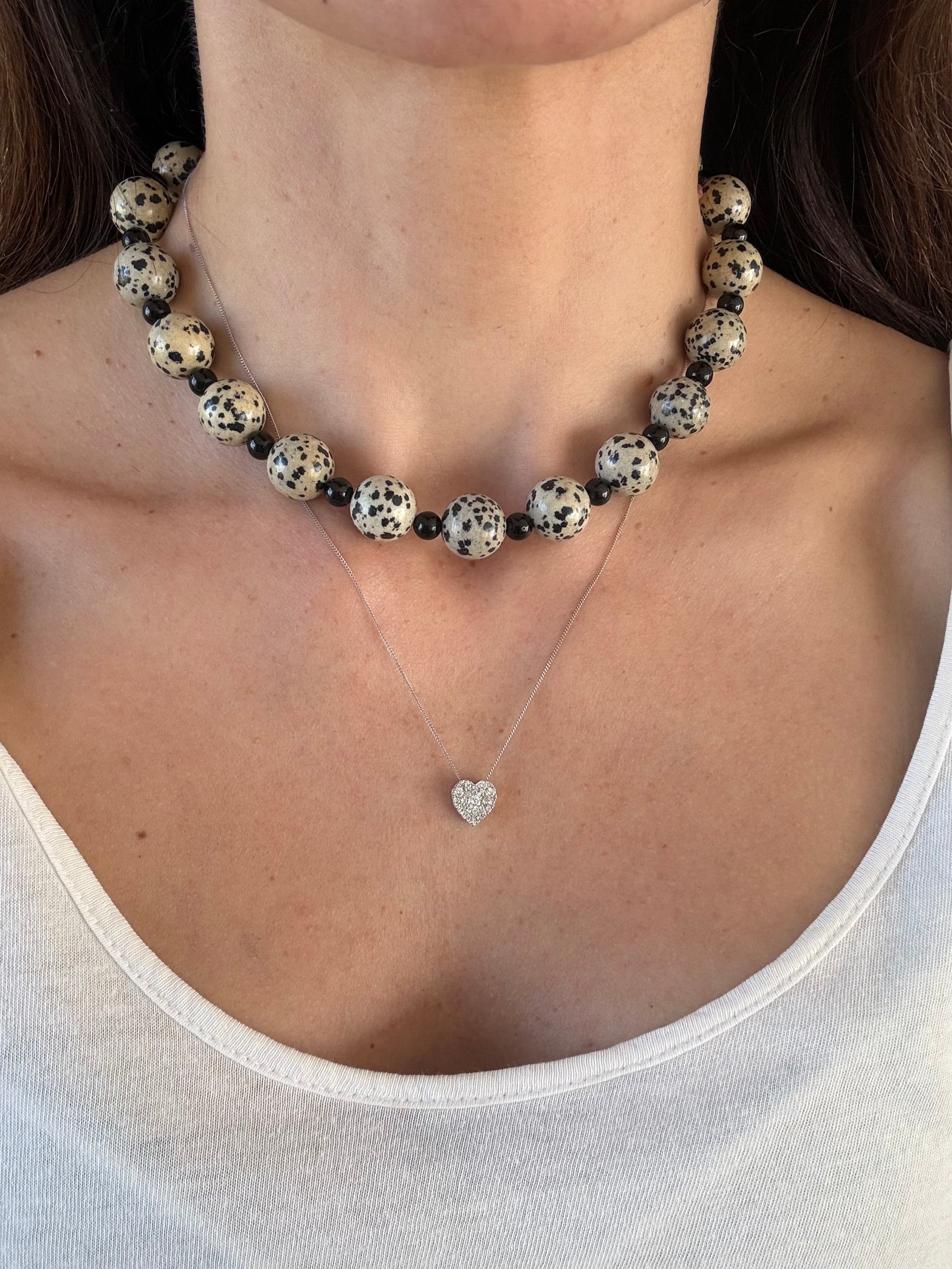 A close-up of a woman's neck and chest wearing a chunky dalmatian jasper necklace.