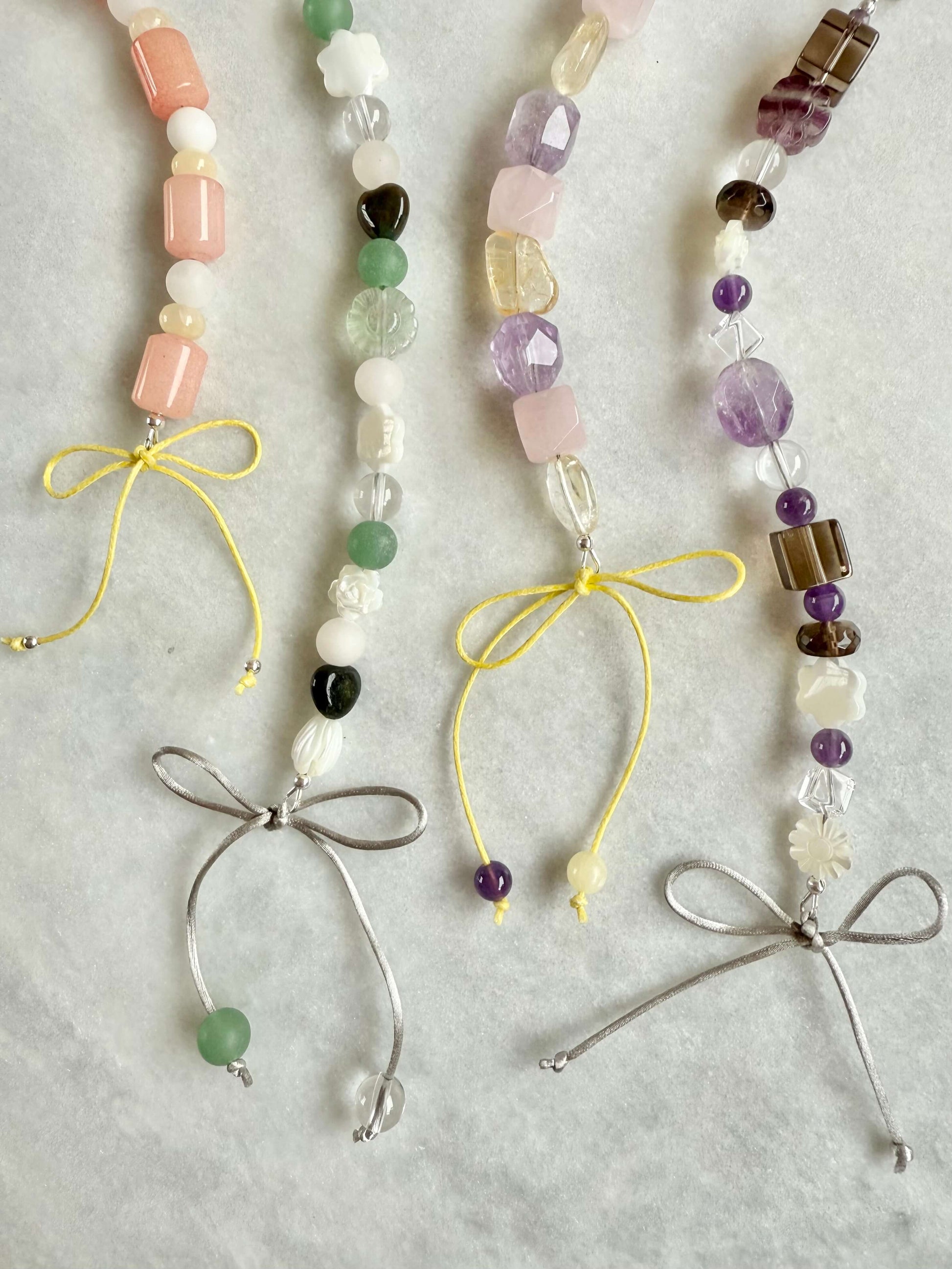 Beaded necklaces with bows on a light gray background