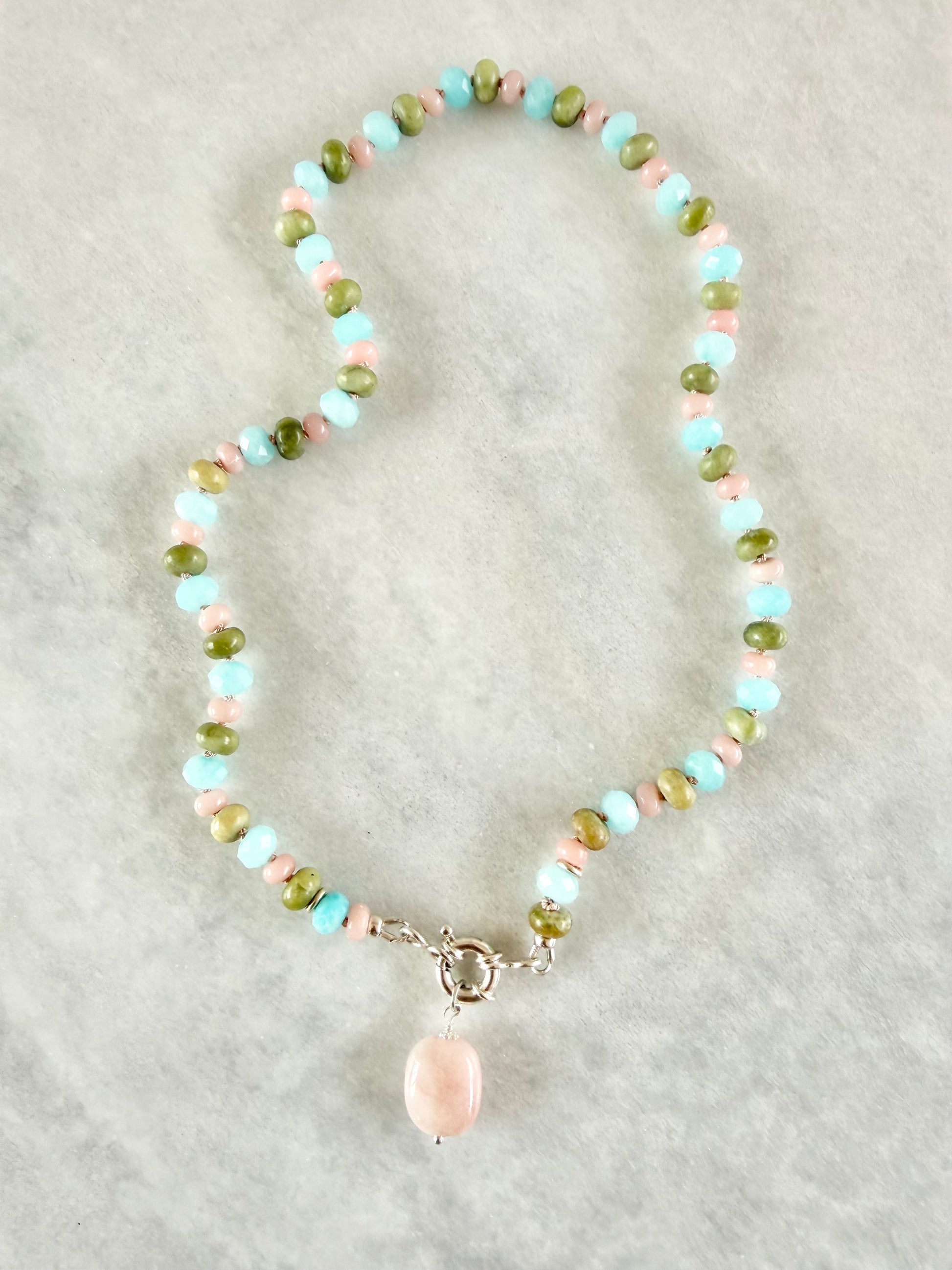 Beaded necklace with a pink pendant on a light gray background