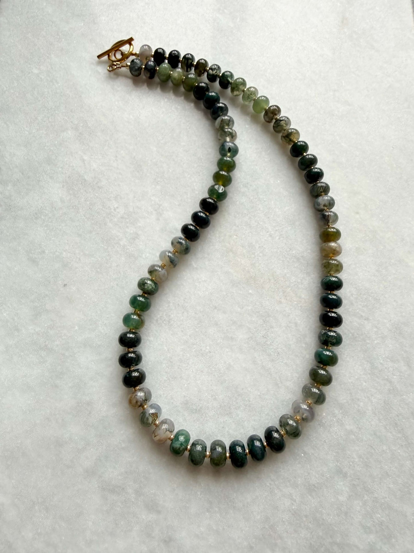 Necklace with green and black beaded chain on a white background
