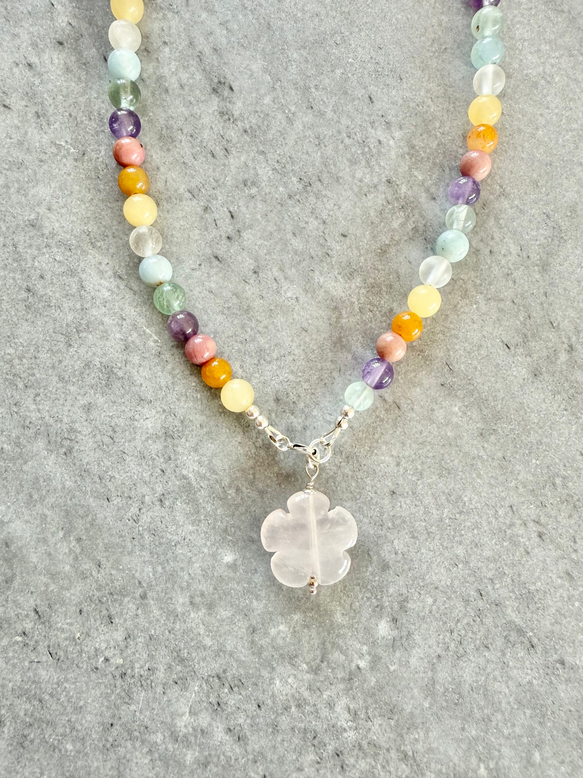 Necklace with multicolored beads and a clear stone pendant on a gray surface