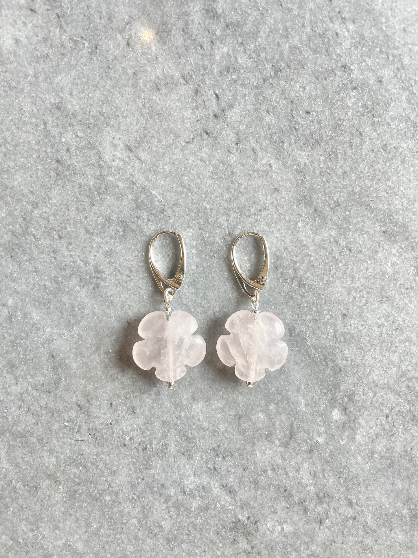 A pair of silver earrings featuring rose quartz flower charms.